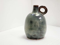 a small blue and brown vase sitting on a white table