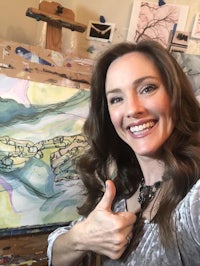 a woman in front of an easel with a thumbs up